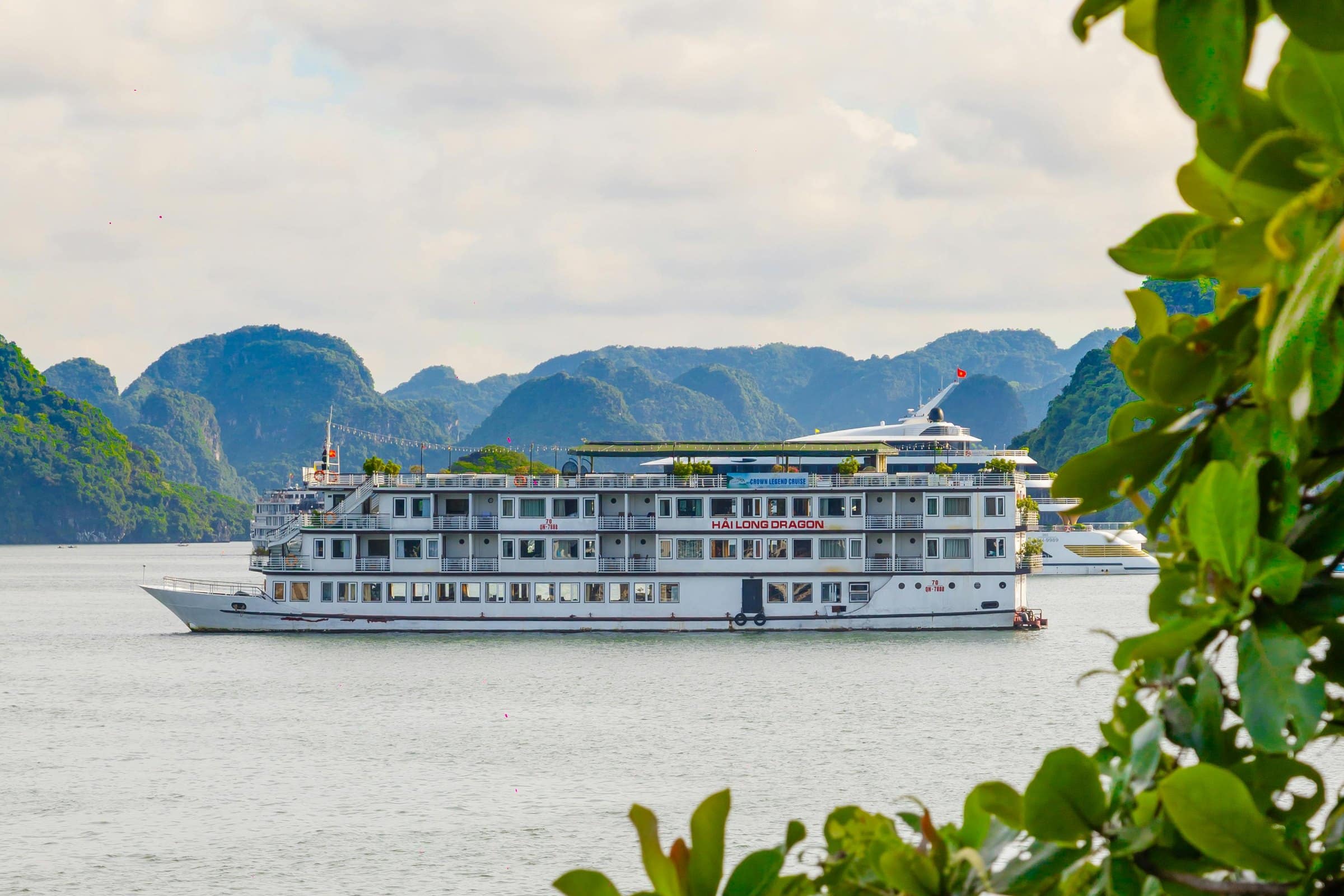 A premium cruise sailing between limestone islands on a calm bay.